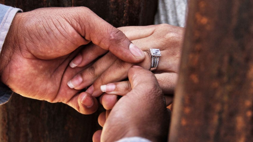 Rogelio gives Miriam her wedding ring as they get married through the border wall between Mexico and the United States, during the “Keep our dream alive” event, in Ciudad Juarez, Chihuahua state, Mexico on December 10, 2017. – Families separated by the border are reunited for three minutes through the fence that separates Ciudad Juarez Park in Mexico and Sunland in New Mexico, United States, during an event called “Keep our dream alive”, organized by the Border Network for Human Rights on the International Human Rights Day. (Photo by Herika MARTINEZ / AFP) (Photo by HERIKA MARTINEZ/AFP via Getty Images)